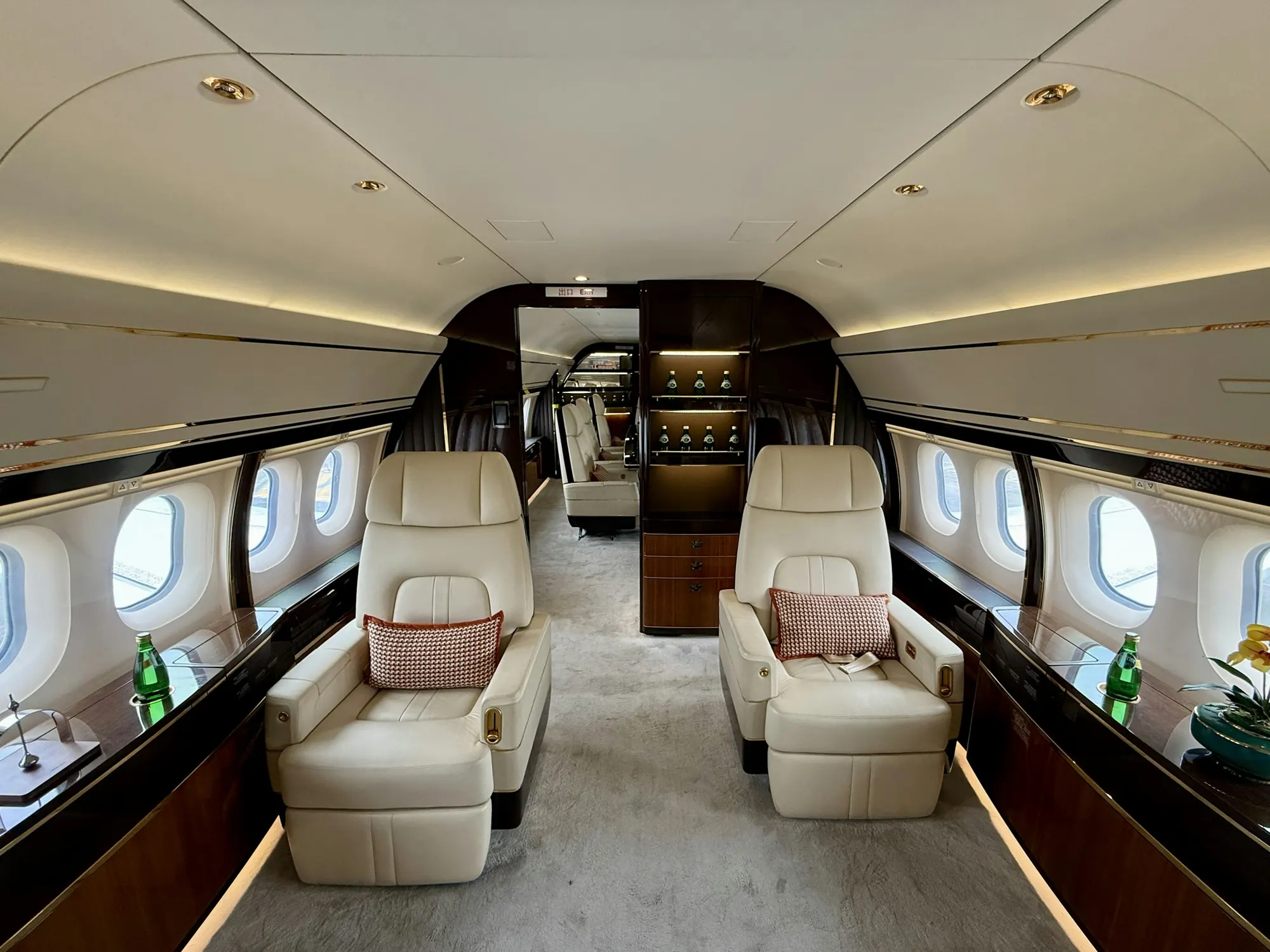 Wide cabin of a large business jet with club seats and a divan