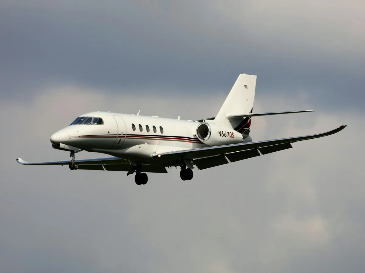 Midsize business jet climbing out under cloud